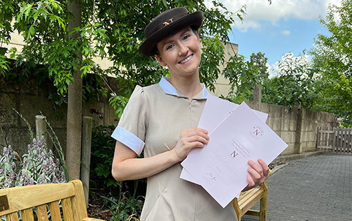 a female Norland Nanny student holding some certificates