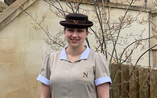 a female student in her formal uniform smiling outside