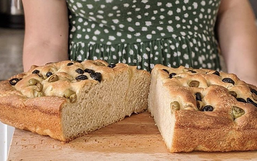 a female student holding a plate of sourdough focaccia that she has made