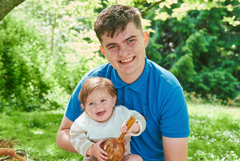 a male Norland Nanny student studying early childhood at Norland holding a baby