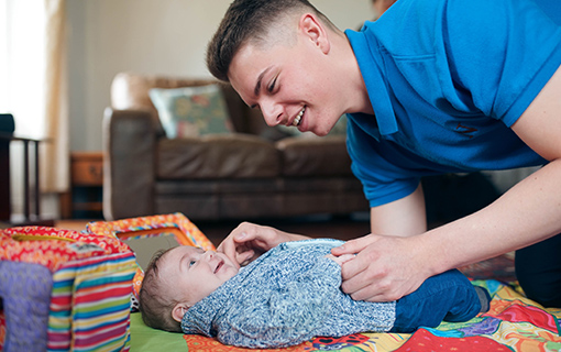 male student looking after baby boy on mat