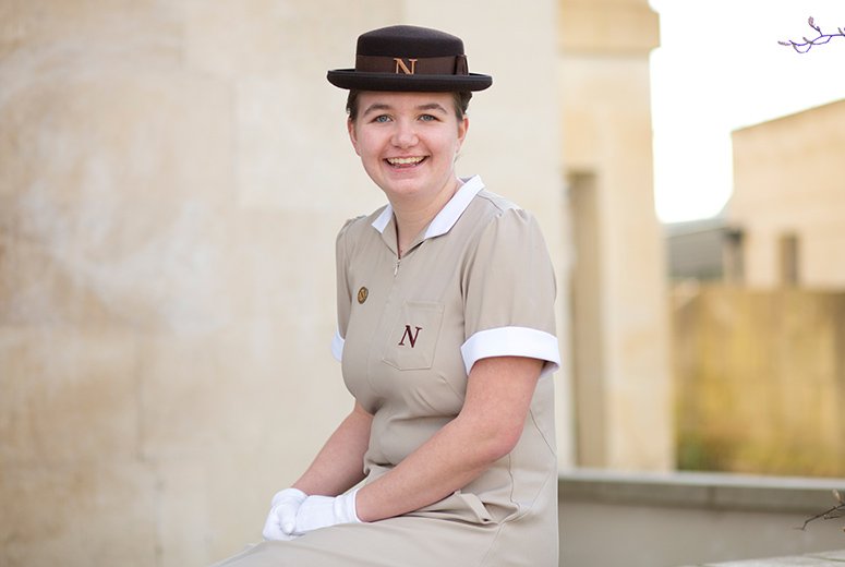 a student in uniform sat on a wall