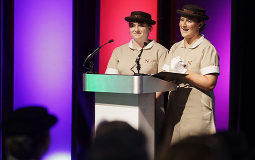 Two students in their Norland uniform speaking at on a stage