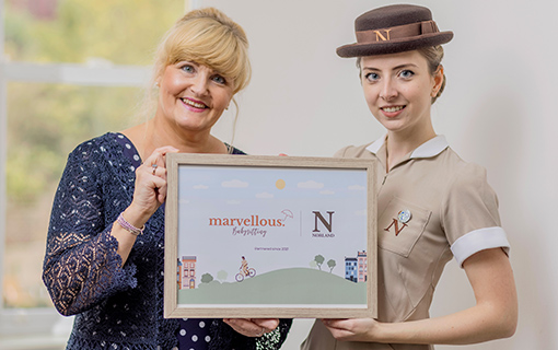 Two females holding a frame announcing the launch of a new babysitting app that offers childcare and babysitting