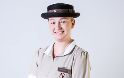 a female international student who is studying an early years degree in Bath, UK in her formal uniform smiling