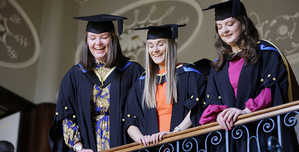 Three Norland graduates looking over a bannister