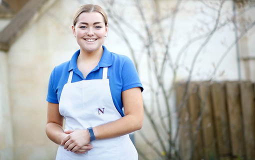 a female student in an apron smiling